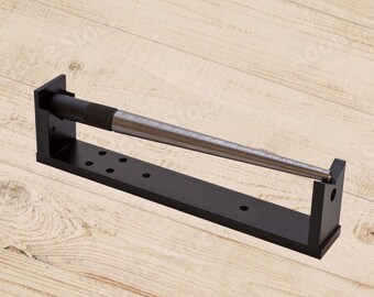 May include: A black metal ring sizer with a silver metal ring mandrel. The mandrel is marked with size numbers.