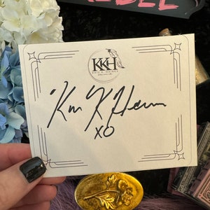 May include: A white card with a black border and a black and white logo that says "KKH Kris K. Haines jewellery & co."  The card has a black signature that says "Kris K. Haines XO".