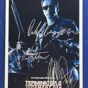 May include: A movie poster for Terminator 2: Judgment Day, featuring Arnold Schwarzenegger in sunglasses, holding a shotgun, and riding a motorcycle. The poster includes the film's title and the text "It's Nothing Personal."