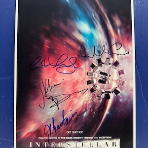 Könnte beinhalten: Ein Filmplakat für "Interstellar" mit Matthew McConaughey, Anne Hathaway, Jessica Chastain und Michael Caine. Das Plakat zeigt eine Weltraumszene mit einer Galaxie und einem Raumschiff. Die Unterschriften der Schauspieler sind sichtbar.