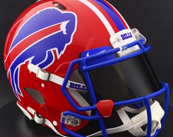 Puede incluir: Casco de fútbol americano rojo brillante con un diseño de rayas azules y blancas. El casco presenta un logotipo de búfalo azul y una máscara facial azul. La palabra "BILLS" está impresa en la máscara.