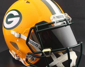 May include: A glossy, yellow football helmet with a green and white stripe and the letter "G" on the side. The helmet has a dark green face mask, a clear visor, and the word "PACKERS" on the chin strap.