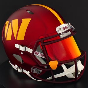 May include: A burgundy American football helmet with a yellow stripe and a large yellow "W" logo. The helmet has a burgundy face mask, a clear visor with a yellow tint, and white chin straps. The visor has the word "COMMANDER" printed on it.