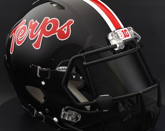 May include: A glossy black football helmet with the word "Terps" in red script on the side. A white and red stripe runs down the center. The helmet has a black facemask and a clear visor. The "BIG" logo is visible.