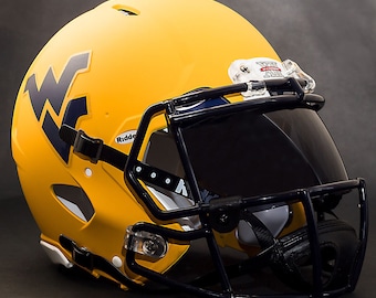 May include: A yellow football helmet with a dark blue "WV" logo on the side. The helmet has a black facemask and a clear visor. The helmet is a Riddell brand.