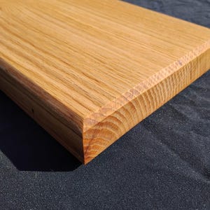 May include: A rectangular wooden cutting board with a light brown finish. The board has a beveled edge and visible wood grain. The cutting board is made of solid wood and is suitable for kitchen use.