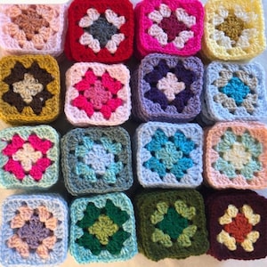May include: A collection of sixteen square crochet motifs arranged in a four-by-four grid. Each square features a multi-coloured yarn pattern with a central cluster and surrounding stitches in various shades including pink, blue, green, yellow, and brown.