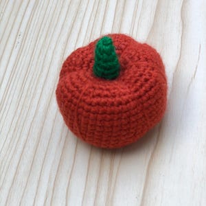 May include: A handmade, crocheted pumpkin in a vibrant orange color with a green stem. The pumpkin is round and has a textured surface, perfect for fall decor. The craft is made with yarn.