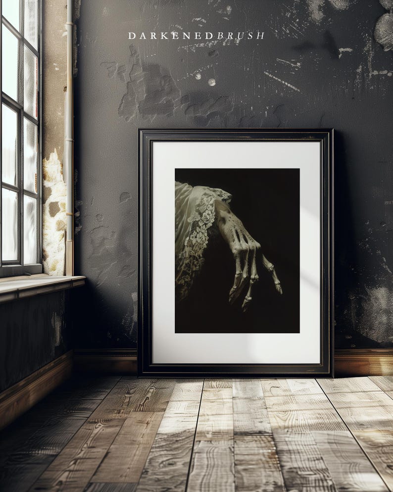 K&ouml;nnte beinhalten: Ein schwarzer Bilderrahmen mit einem wei&szlig;en Passepartout. Das Bild zeigt eine skelettartige Hand, die aus einem wei&szlig;en Stoff herausragt. Der Hintergrund ist dunkel.
