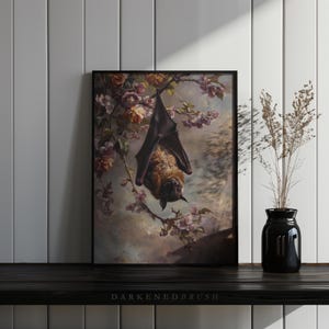 May include: A framed print depicting a brown bat hanging upside down from a branch of a flowering tree. The bat is surrounded by pink and white blossoms. The background is a soft, muted blue.