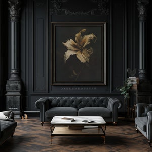 May include: A dark, luxurious living room with black walls, a black velvet sofa, and a black coffee table. A framed print of a single, dried flower hangs on the wall. The room is decorated with gold accents and a black and gold bookshelf.