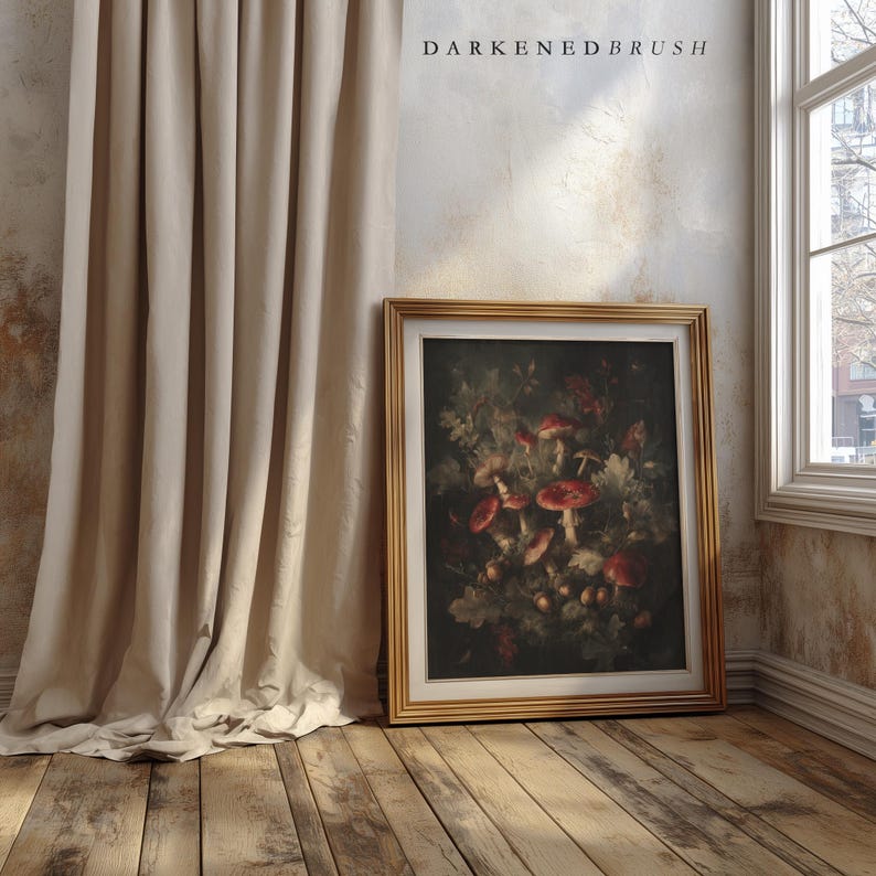 Op de afbeelding: Een ingelijste botanische prent met rode paddenstoelen en bladeren, in een gouden lijst. Het kunstwerk leunt tegen een muur naast een beige gordijn. De tekst "DARKENDEDBRUSH" staat bovenaan.