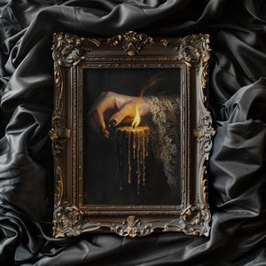 May include: Ornate framed artwork featuring a hand with long, black nails, lighting a candle. The candle's wax drips down, and the artwork is set against a dark, draped background. The frame has a detailed, antique design.