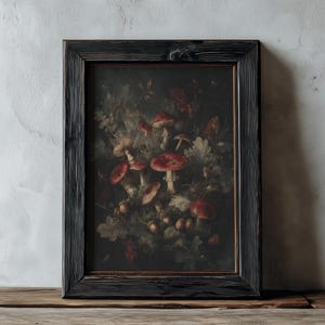 Op de afbeelding: Een ingelijste kunstdruk met een donker, sfeervol stilleven van roodkapjes en bladeren. Het kunstwerk is geplaatst tegen een donkere achtergrond en omlijst in een zwart houten frame met textuur. De tekst "DARKENEBRUSH" staat bovenaan.