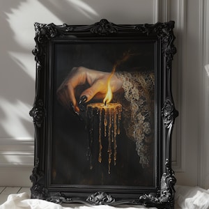 May include: A framed painting with a dark aesthetic. The artwork depicts a hand with long, black nails holding a lit candle with dripping wax. The frame is ornate and black, with the text "DARKENEBRUSH" at the top.