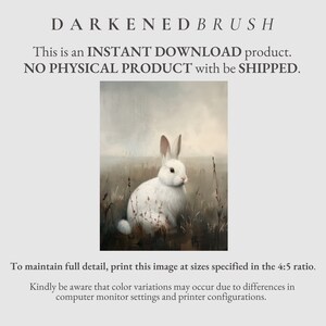 May include: A white rabbit with brown spots sits in a field of tall grass. The rabbit is looking to the right of the image. The background is a soft, muted gray.
