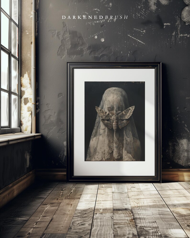 May include: A black framed print of a woman wearing a white veil with a large moth covering her face. The background is dark and the image has a vintage feel.