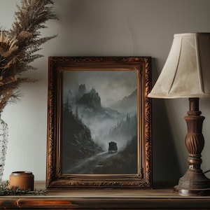 K&ouml;nnte beinhalten: Ein gerahmtes Gem&auml;lde einer dunklen, nebeligen Landschaft mit einem Schloss in der Ferne und einer Kutsche, die auf einer Stra&szlig;e durch den Nebel f&auml;hrt.