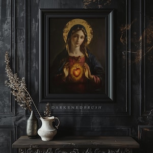 May include: A framed painting of a woman with a halo holding a heart in her hands. The woman is wearing a blue robe and the heart is glowing red. The painting is set against a dark background with the text "DARKENED BRUSH" below the frame.