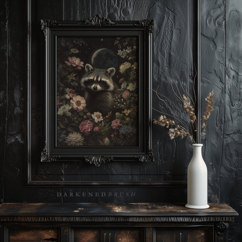 May include: A framed print of a raccoon surrounded by flowers and a crescent moon. The frame is black with ornate detailing. The background is a dark wood paneling.