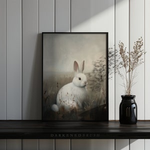 May include: A framed painting of a white rabbit sitting in a field of tall grass. The rabbit has pink eyes and a long, fluffy tail. The background is a soft, muted brown.