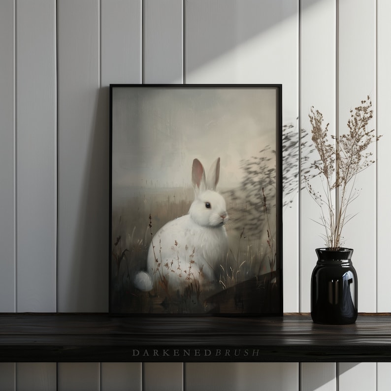 May include: A framed painting of a white rabbit sitting in a field of tall grass. The rabbit has pink eyes and a long, fluffy tail. The background is a soft, muted brown.
