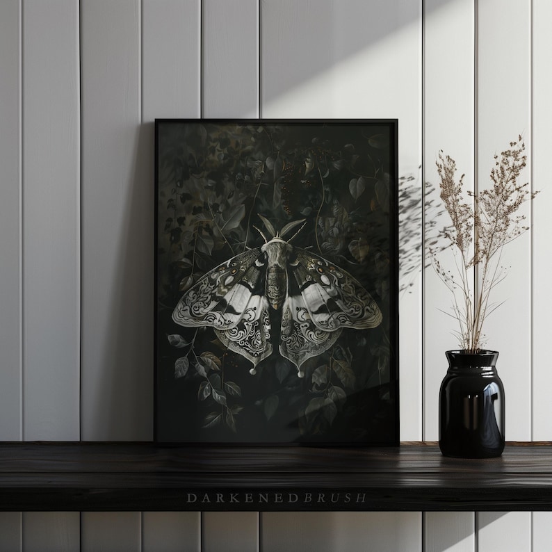 May include: A black framed print of a detailed illustration of a moth with intricate patterns on its wings. The moth is set against a dark background with foliage.