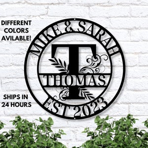 May include: Black metal circle sign with the names Mike & Sarah and the last name Thomas. The sign also includes the year 2023 and the word "EST".