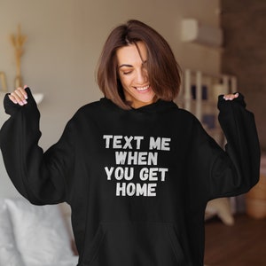 May include: Black hooded sweatshirt with the text "Text Me When You Get Home" in white.