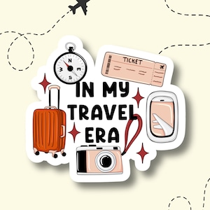 May include: A sticker featuring travel-related icons: a suitcase, camera, compass, ticket, and airplane window. The phrase "IN MY TRAVEL ERA" is written in bold letters, with a dotted line and airplane graphic.