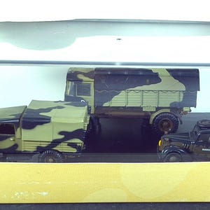 May include: A boxed Oxford Military model set featuring three military vehicles. The models have a camouflage pattern in shades of green, brown, and black. The box has the Oxford logo and the scale 1:76.