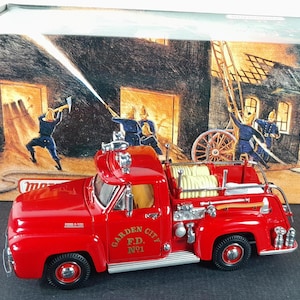May include: Red toy fire truck with a hose and ladder, labeled "GARDEN CITY F.D. NO.1", on a white background with a box showing a fire scene.