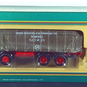 Puede incluir: Modelo de un conjunto de camión y remolque Road Services Caledonian verde y rojo. El camión tiene una zona de carga cubierta con el texto "Road Services Caledonian Ltd. Dumfries Fleet No. 271". El conjunto está en una caja verde, roja y blanca.