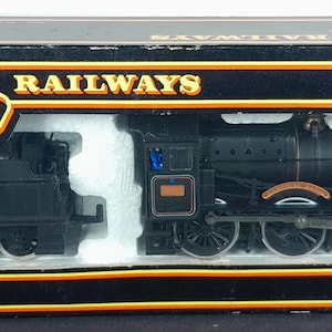 May include: A boxed Mainline Railways OO gauge model train set. The black locomotive and tender have red and gold detailing. The box is black with gold lettering and trim. The model is an authentic OO gauge model.