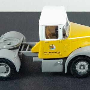 Op de afbeelding: Een gele en witte vintage speelgoedvrachtwagen met grijze spatborden en wielen. De vrachtwagen heeft de tekst "Shell-Mex and B.P. Ltd" op de zijkant. Een miniatuur replica van een klassiek voertuig.