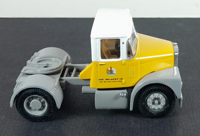 Op de afbeelding: Een gele en witte vintage speelgoedvrachtwagen met grijze spatborden en wielen. De vrachtwagen heeft de tekst "Shell-Mex and B.P. Ltd" op de zijkant. Een miniatuur replica van een klassiek voertuig.