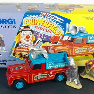 Puede incluir: Un modelo Corgi Classics Chipperfields Circus Land Rover rojo y azul, con figuras de payasos y una caja con imágenes de circo. El camión modelo tiene un altavoz y el texto "Europe's Largest".