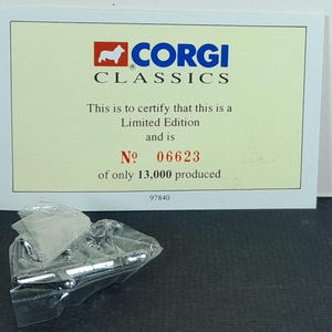 Op de afbeelding: Een Corgi Classics Limited Edition certificaat met nummer 06623, van slechts 13.000 geproduceerd. Het certificaat is cr&egrave;mekleurig met het Corgi-logo en tekst. Een kleine, doorzichtige plastic zak bevat een zilverkleurig object.