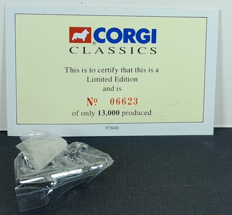 Op de afbeelding: Een Corgi Classics Limited Edition certificaat met nummer 06623, van slechts 13.000 geproduceerd. Het certificaat is cr&egrave;mekleurig met het Corgi-logo en tekst. Een kleine, doorzichtige plastic zak bevat een zilverkleurig object.