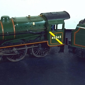 Puede incluir: Un modelo detallado de tren de vapor verde y negro, con detalles en rojo y dorado. La locomotora muestra el número 45565. El ténder de carbón está lleno de una sustancia oscura y presenta un emblema circular.