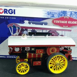May include: A Corgi Limited Edition Burrell Showman's model steam engine. The model is red, black, and gold with yellow wheels. The box reads "Vintage Glory" and is for adult collectors.