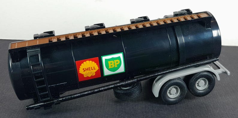 Op de afbeelding: Een zwart tankwagenmodel met een bruine bovenkant en een ladder aan de zijkant. De tankwagen heeft de Shell- en BP-logo's op de zijkant. De vrachtwagen heeft zes wielen en een grijs chassis.