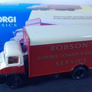 Op de afbeelding: Een rode en witte speelgoedtruck met de tekst "Robson's Carlisle, London & Glasgow Service" aan de zijkant. De truck is een model van Corgi Classics.