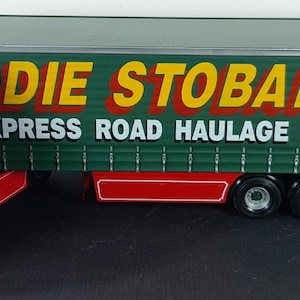 Könnte beinhalten: Ein grüner und gelber Spielzeug-LKW mit der Aufschrift "Eddie Stobart Ltd Express Road Haulage Specialist" an der Seite. Der LKW ist ein Modell eines Sattelzuges.