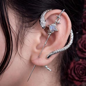 Puede incluir: Una taza de cerámica blanca con un asa negra y el texto "But First, Coffee" en negrita negra. La taza se encuentra sobre un fondo neutro, resaltando su diseño sencillo.