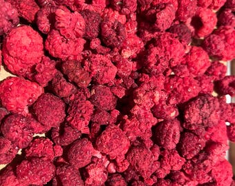 May include: Close-up of a pile of dried raspberries. The raspberries are a deep red color, with a slightly textured surface. The image is well-lit, showing the details of the fruit.