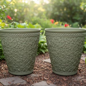 May include: Two olive green plant pots with embossed floral patterns. The pots have a rope-like design around the rim and are set on a stone path in a garden setting. The pots are ideal for planting flowers.