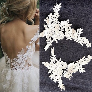 May include: Two white lace appliques with floral designs. The appliques are perfect for adding a touch of elegance to any project.