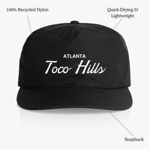 May include: Black snapback hat with white text that reads "ATLANTA Toco Hills". The hat is made of 100% recycled nylon and is quick-drying and lightweight.