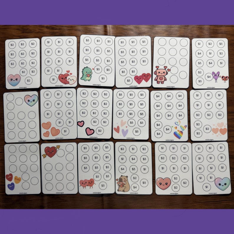 May include: A collection of eighteen rectangular white savings challenge cards arranged in three rows. Each card features a grid of circles containing dollar amounts or blank spaces, decorated with colorful cartoon illustrations of hearts, animals, and robots.
